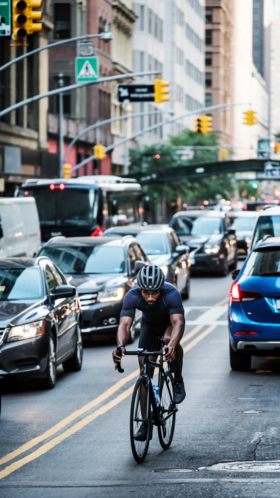 Man cycling on a busy city road in the USA with cars and traffic around him.